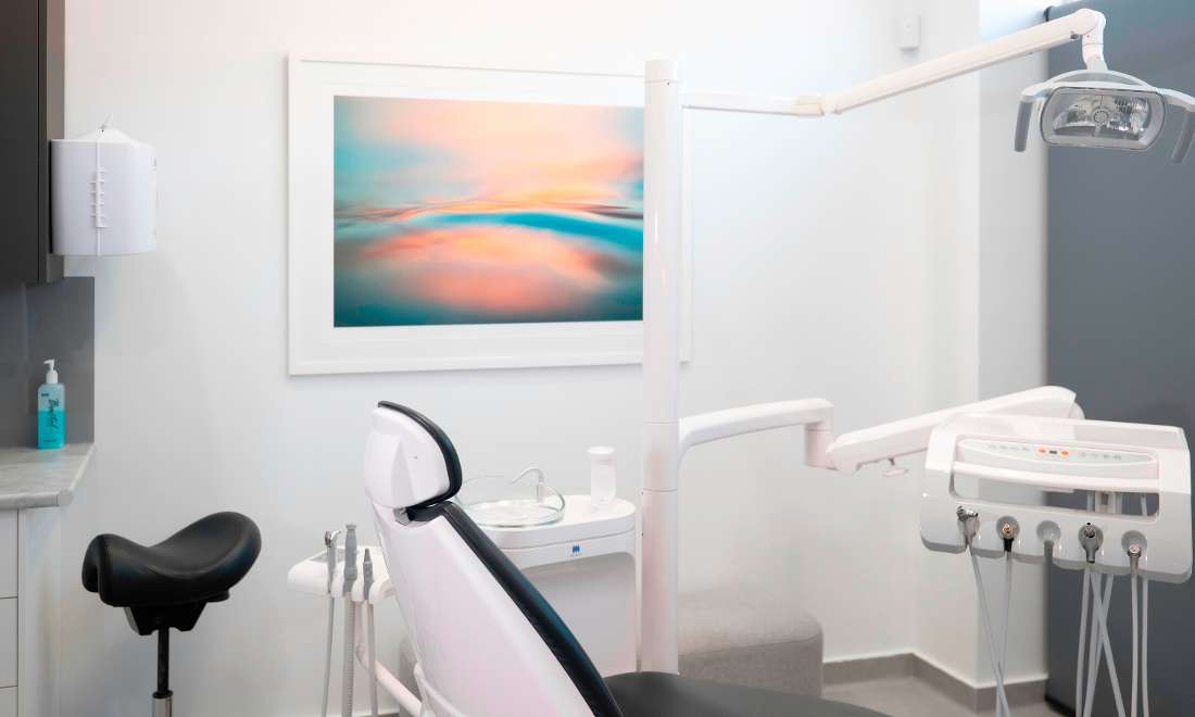 Surgery one at Waterways Dental. Black and white dental chair sitting in a bright, white room, with a beautiful image on the wall of the ocean.